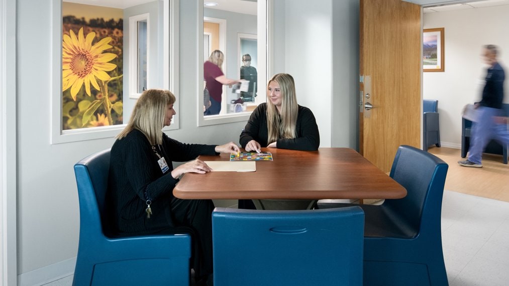 Psychiatric nurse and patient in a room, playing a board game